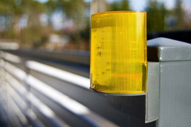 Close-up of a yellow warnig light mounted on driveway gate.